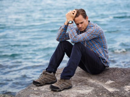 man thinking on rock by water